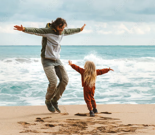 Schmuckbild "Work-Life-Balance in der Niederlassung" Vater und Sohn hüpfen am Strand in die Höhe