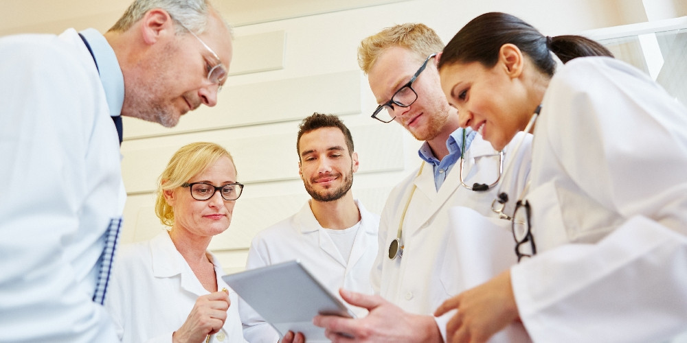 Ärzte im MVZ Eine Gruppe Ärzte beugt sich über ein Tablet