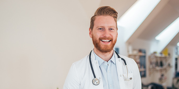 Junger Arzt Lachender junger Arzt in Praxis