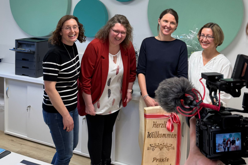 sympatisches Praxisteam mit Ärztin vor der Kamera