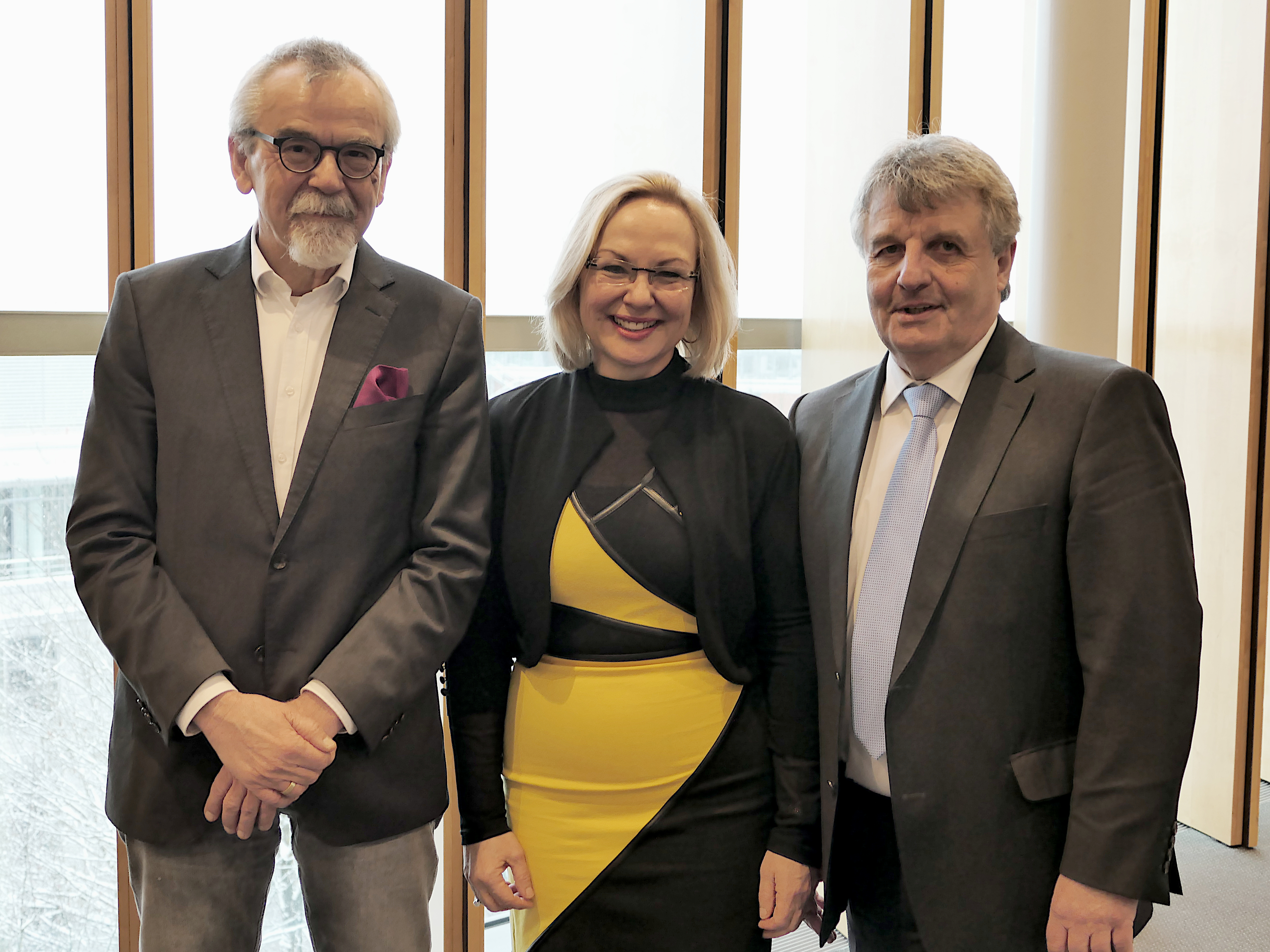 Gruppenbild mit zwei Männern und einer Frau zwischen ihnen